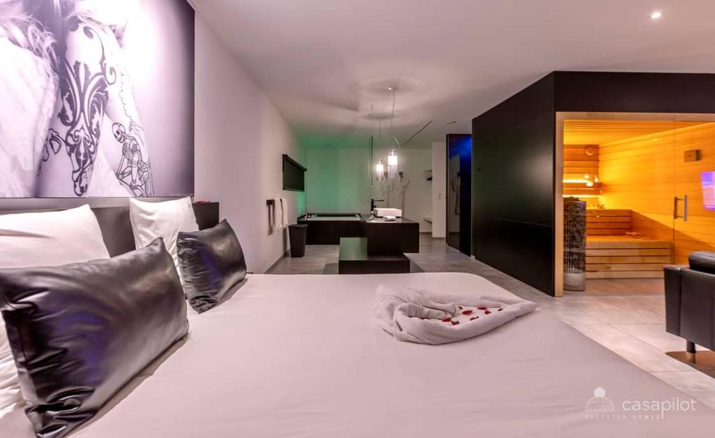 a bedroom with a large white bed and a living room at Oduo in Sart-lez-Spa