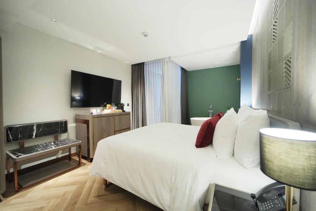 A second angle on the bedroom showing the bed, television wall and bedside phone.