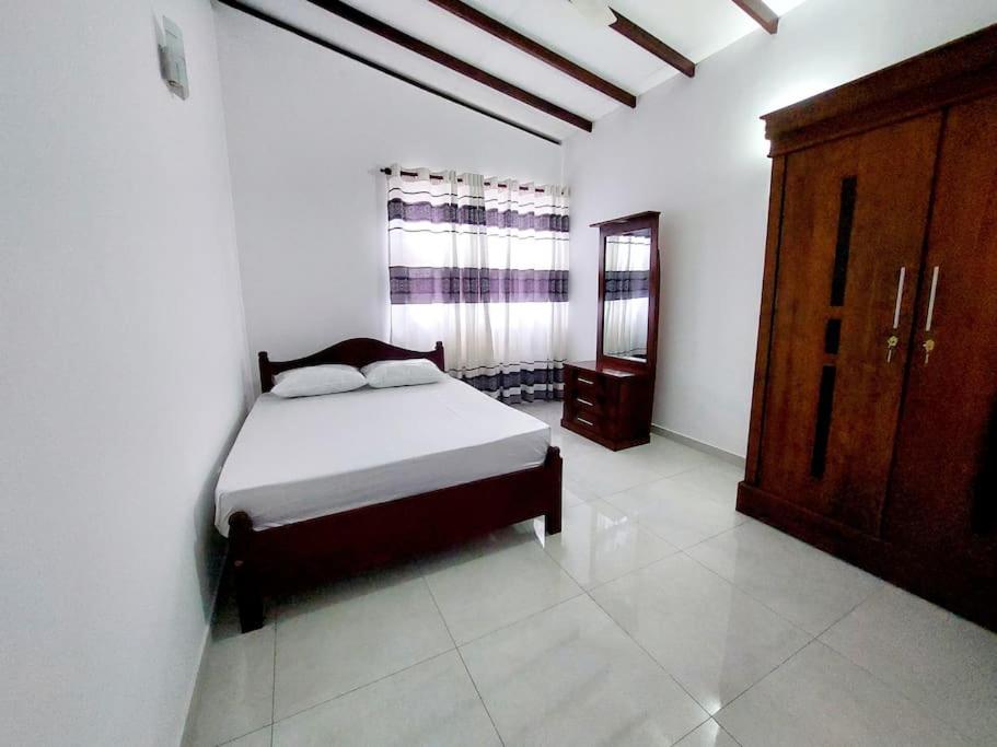 a bedroom with a bed and a wooden cabinet in it at Comfortable Stay in Colombo in Rajagiriya