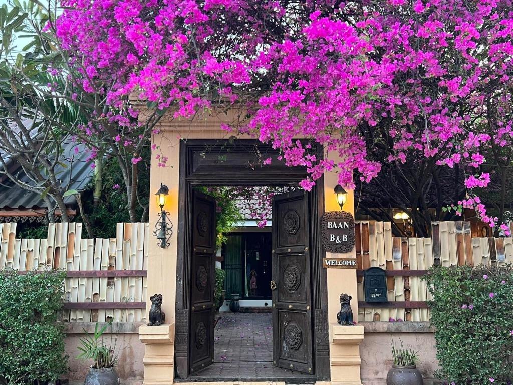 een ingang naar een gebouw met roze bougainvillea bij Baan B&B Sukhothai in Sukhothai