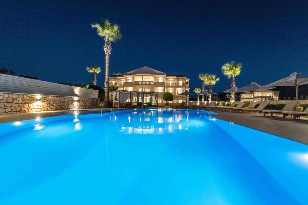 a large swimming pool in front of a house at night at San Giovanni Beach Resort and Suites in Lefkada