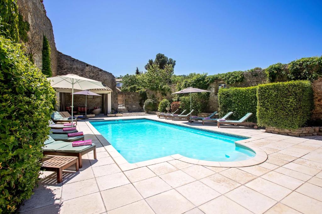 une piscine avec chaises et parasols dans une cour dans l'établissement La Maison Des Vignes - Gite Lavande - Luxury Gite with Air Conditioning, à Tourouzelle