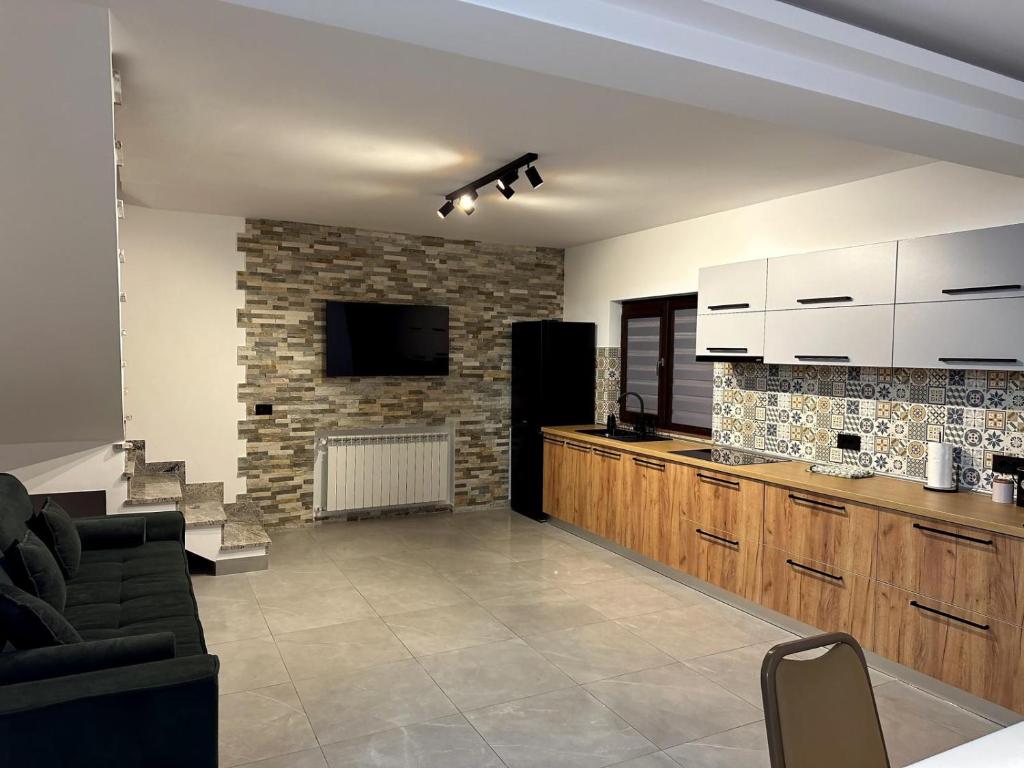 a kitchen with white cabinets and a stone wall at North Kaban in Borşa