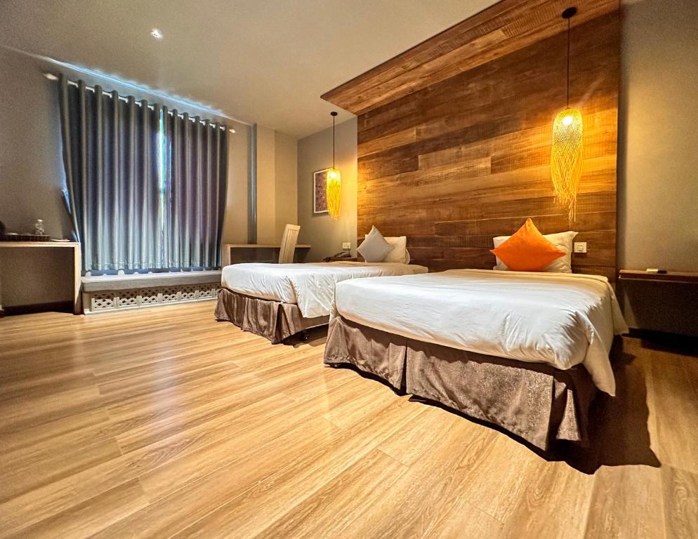 a hotel room with two beds and a wooden wall at Goda Boutique Hotel in Hoi An