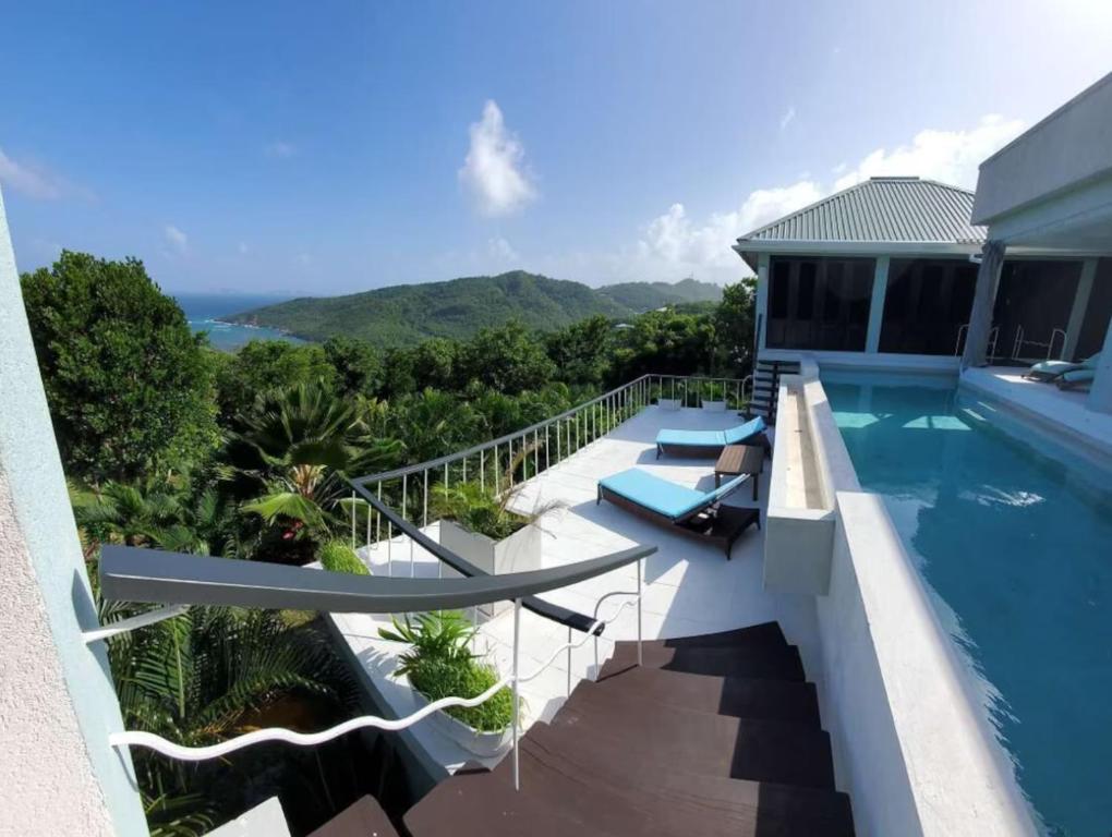 a house with a swimming pool with mountains in the background at Lux Villa w/ Stunning Panoramic Ocean Views in Bequia