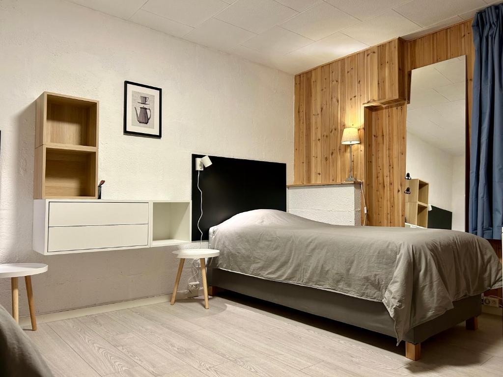 a bedroom with a bed and two tables and a mirror at Simple room in Trondheim