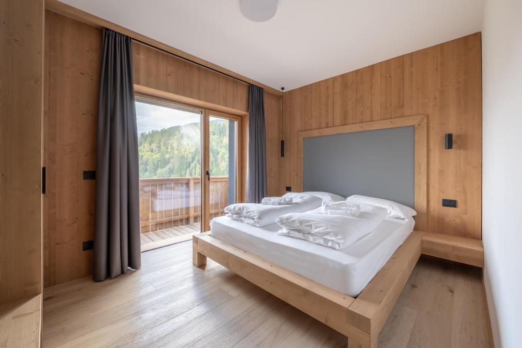 a bedroom with two beds and a large window at aMa Dolomiti Resort in Vigo di Cadore