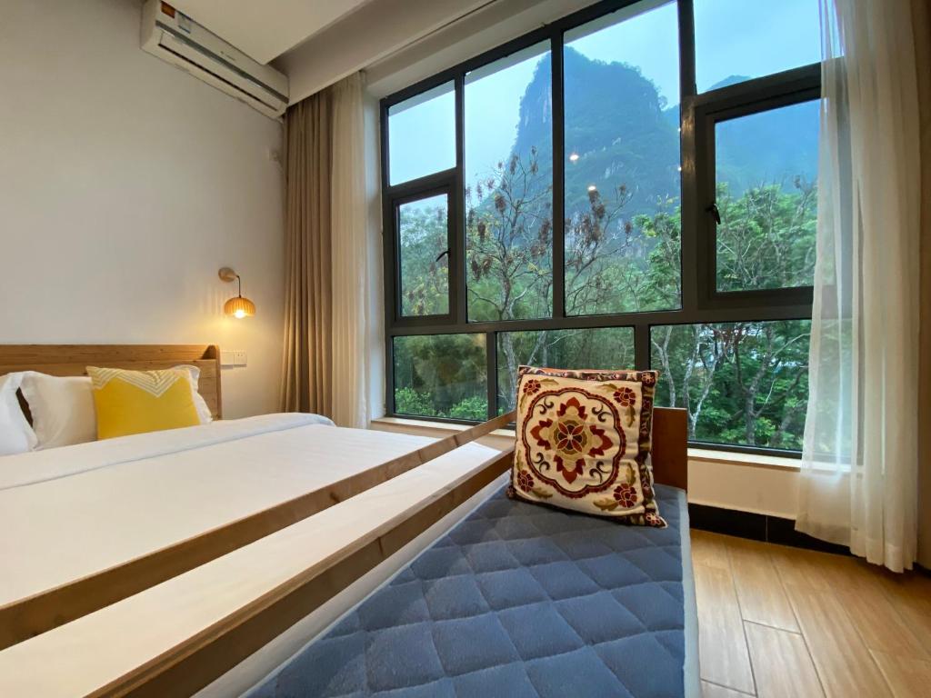 um quarto com uma cama e uma grande janela em 林涧小栈Linger house em Yangshuo