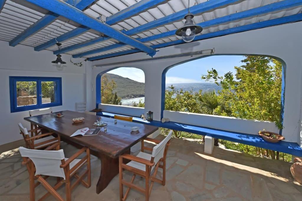 comedor con mesa y sillas de madera y ventanas grandes en La Casa Di Maryolo Holiday House, en Kardhianí