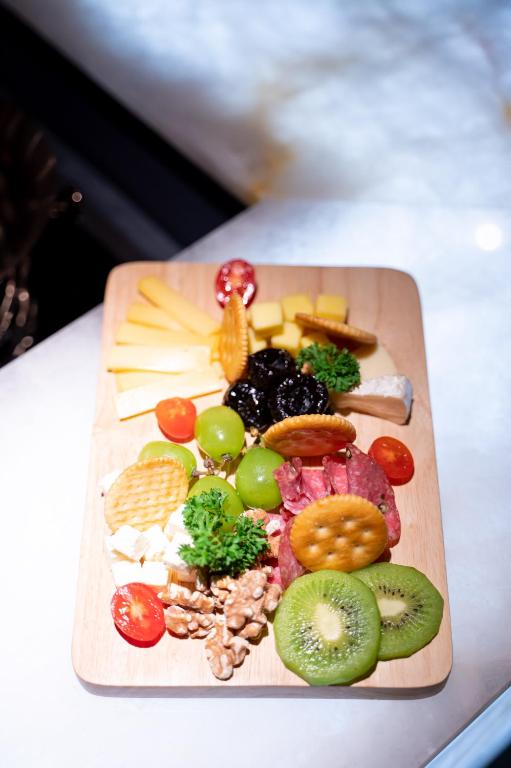 A fruit, cheese, cracker, and nut board arranged on a wooden serving board.