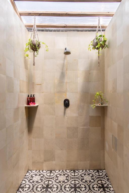 a bathroom with a shower with plants on shelves at Bale Sampan Boutique Bungalows in Gili Trawangan