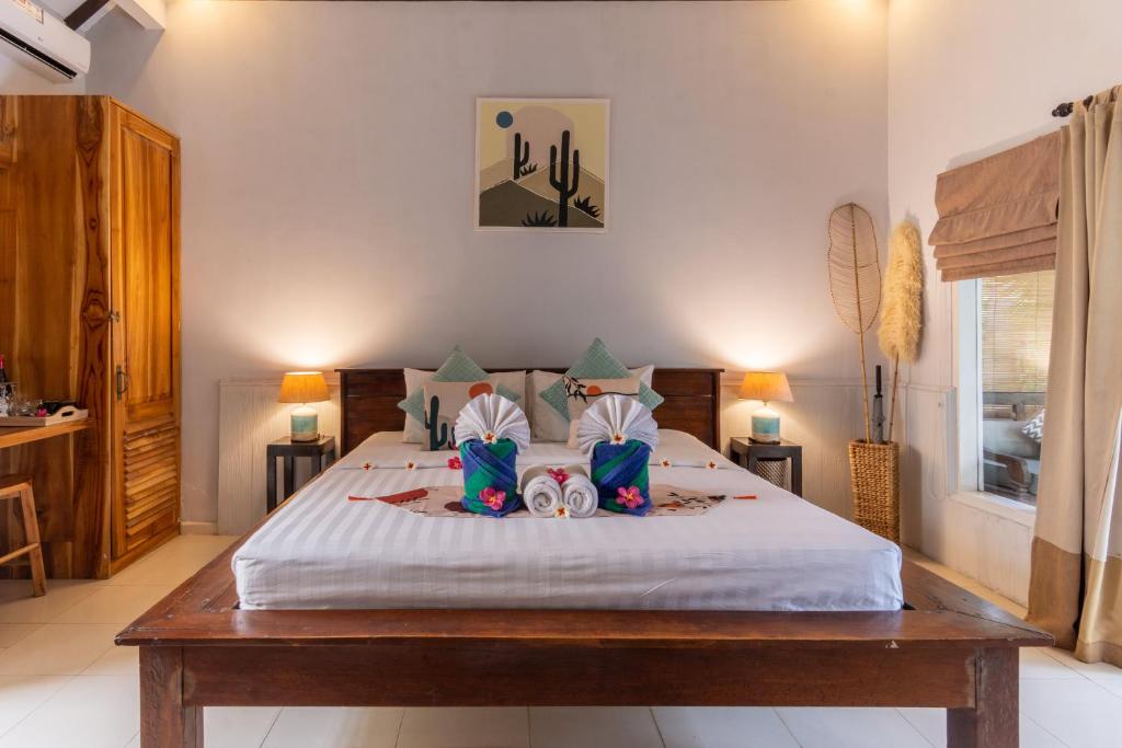 a bedroom with a large bed with two pairs of slippers at Bale Sampan Boutique Bungalows in Gili Trawangan