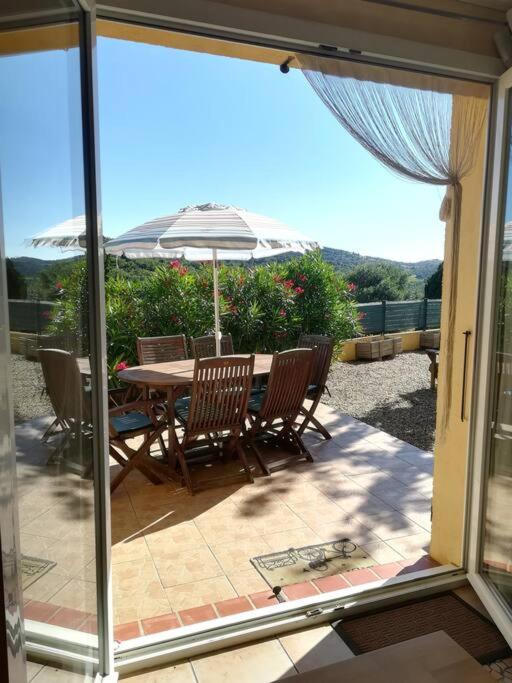un patio avec une table, des chaises et un parasol dans l'établissement Gîte Le Bel-Estar, à Bélesta