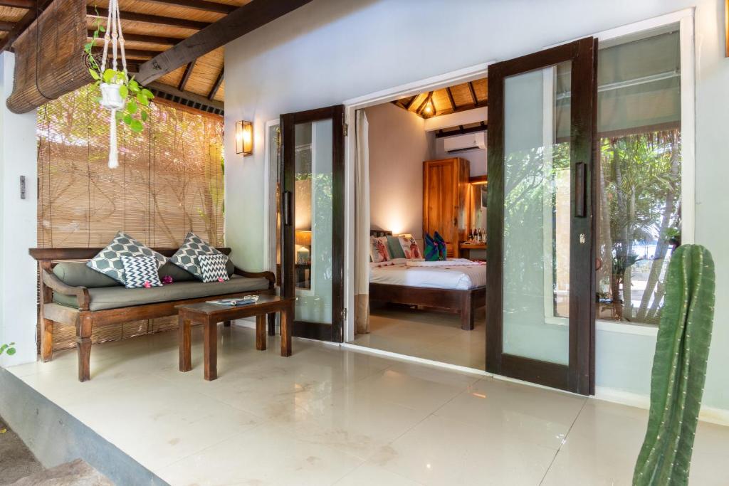 a living room with a couch and a bed in a room at Bale Sampan Boutique Bungalows in Gili Trawangan