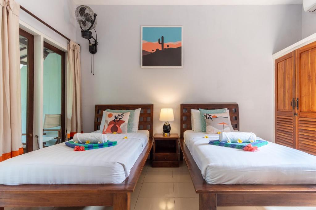 two beds in a room with two windows at Bale Sampan Boutique Bungalows in Gili Trawangan