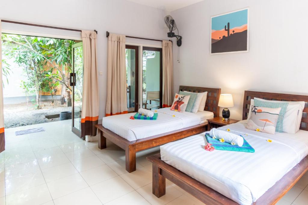 two beds in a room with a view of the ocean at Bale Sampan Boutique Bungalows in Gili Trawangan