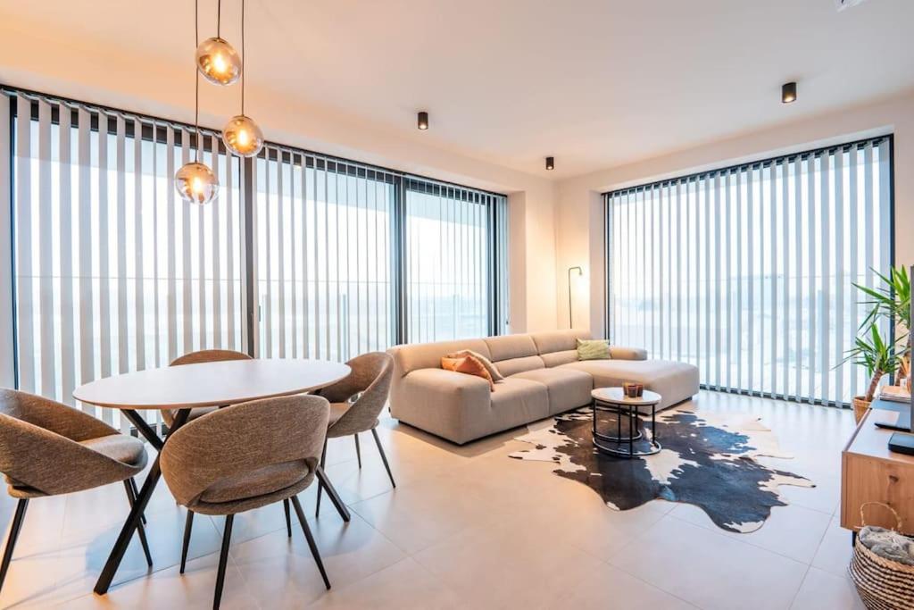 - un salon avec un canapé, une table et des chaises dans l'établissement Prachtig appartement met zwembad en fitness, à Ostende