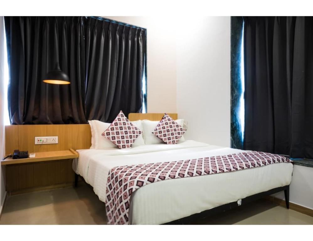a bedroom with a bed with two pillows on it at Hotel Saarthi Inn, Surat in Surat