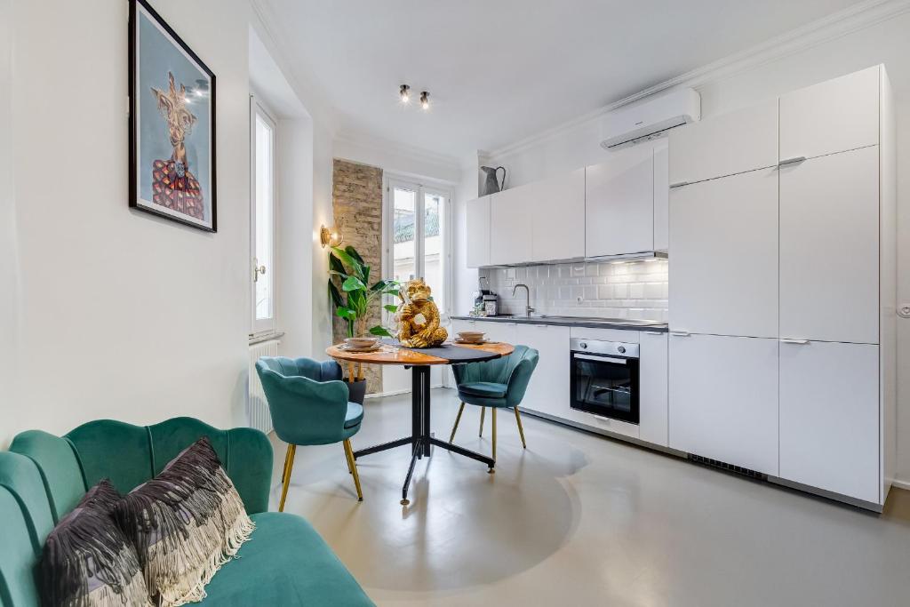 una cucina con mobili bianchi, tavolo e sedie di Klioos Apartment Testaccio a Roma