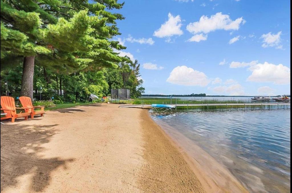 einen Strand mit zwei Stühlen neben einem Wasserkörper in der Unterkunft New! The Stone House On Pelican Lake in Breezy Point