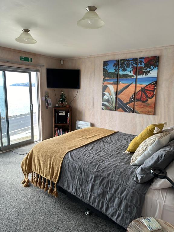 a bedroom with a large bed and a television at Te Mata Bay Seaviews in Tapu