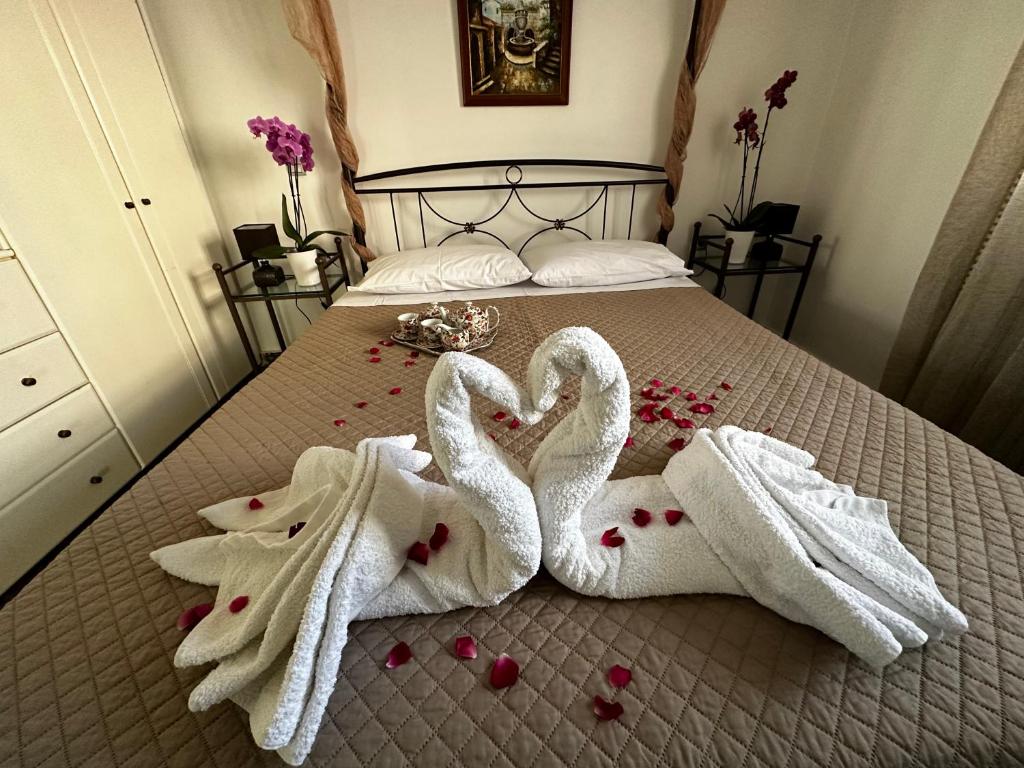 dwa łabędzie owinięte w ręczniki na łóżku z różami w obiekcie A flower house w mieście Mantoúkion