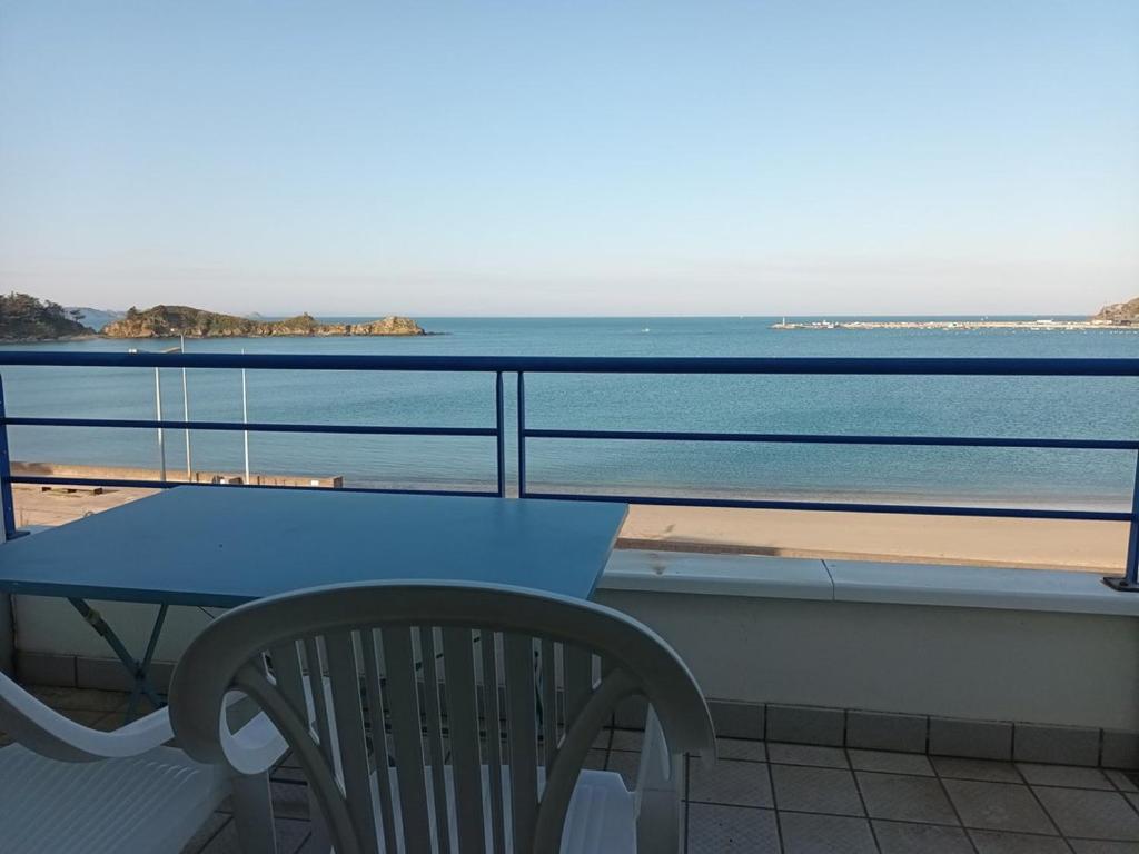 una mesa y una silla en un balcón con vistas a la playa en 514 - Appartement 1 chambre vue mer en bordure de la plage du centre d'Erquy, en Erquy