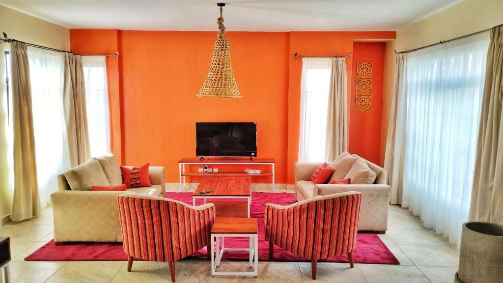 a living room with orange walls and a table and chairs at Swara Ranch Nanyuki in Nanyuki