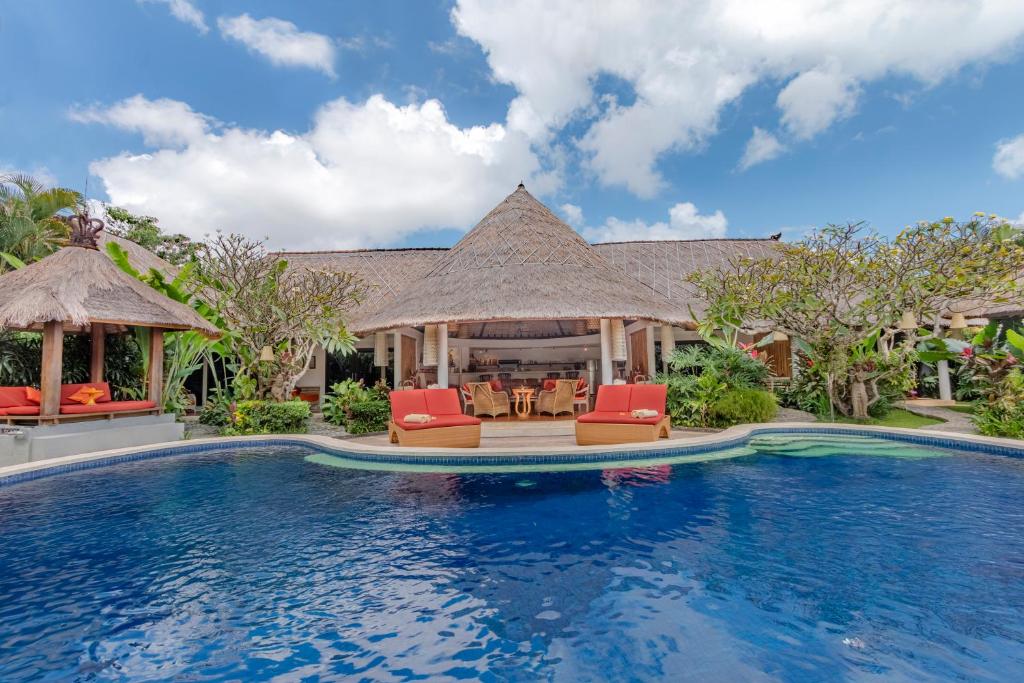 una piscina en un complejo con sillas y mesas en Bali Akasa Villa en Seminyak