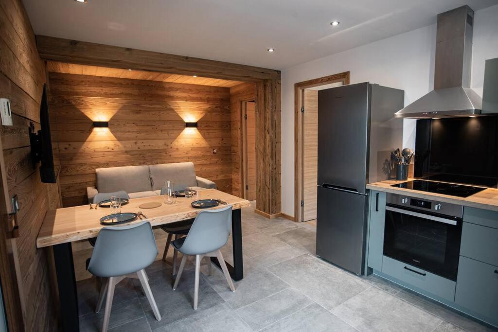 une cuisine avec une table avec des chaises et un réfrigérateur dans l'établissement Appartement neuf proche d'Auron avec accès PMR, à Saint-Étienne-de-Tinée