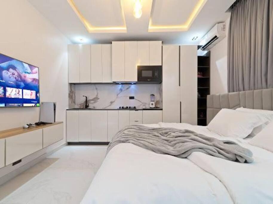 a bedroom with a white bed and a tv at luxury studio apartment in Lekki