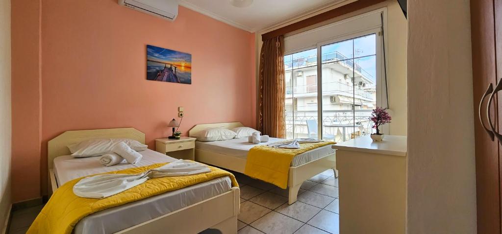 a room with two beds and a window at Chariclia Hotel in Paralia Katerinis