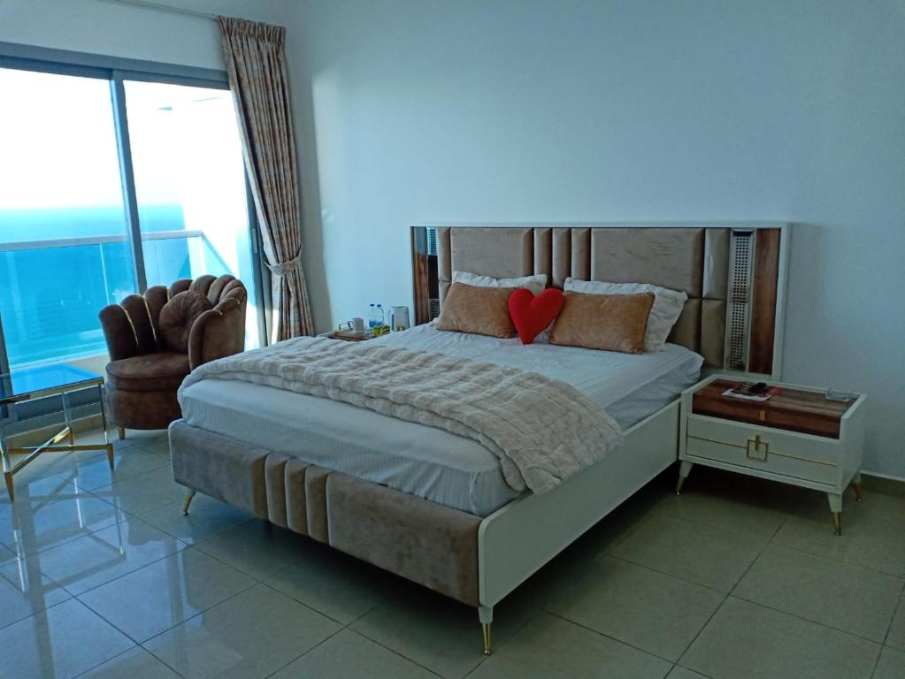 a bedroom with a large bed and a chair at 30 R1 Single 1 Master Room in 3 bedroom apartment with attached washroom and balcony with fantastic sea view 30 R1 غرفة مفردة 1 ماستر في شقة 3 غرف نوم مع حمام ملحق وشرفة بإطلالة رائعة على البح in Ajman 