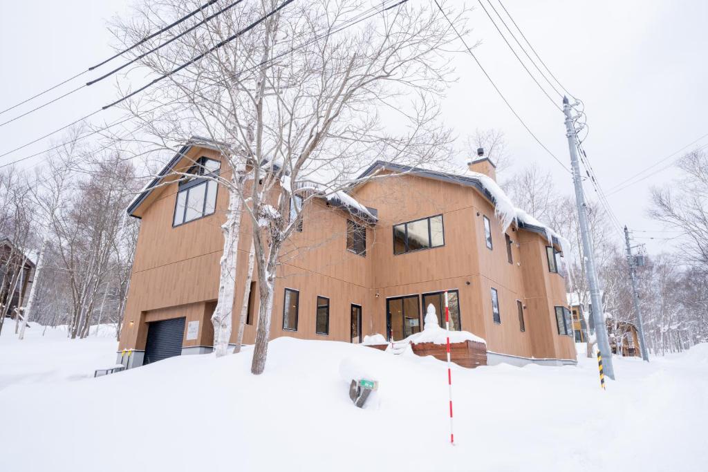 a house in the snow next to a power pole at Yuki Usagi - walking distance to Rusutsu Resort in Rusutsu
