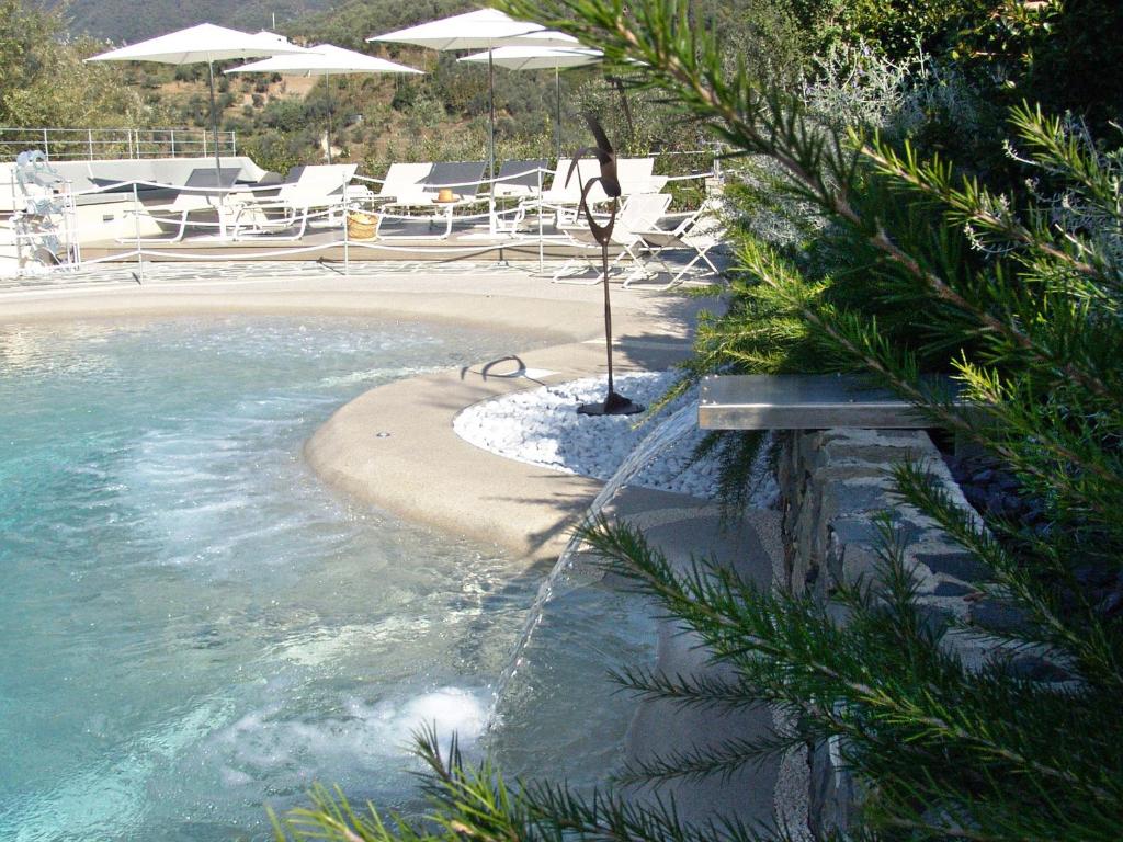 una piscina con una playa con sillas y sombrillas en Villanova Apartments - Nature & Wellness, en Levanto