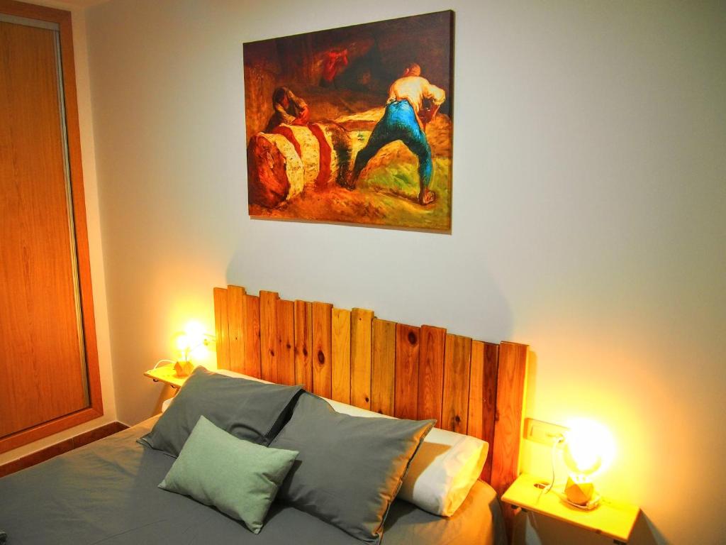 1 dormitorio con 1 cama con una pintura en la pared en Alojamiento Rural Los Gancheros, en Tragacete
