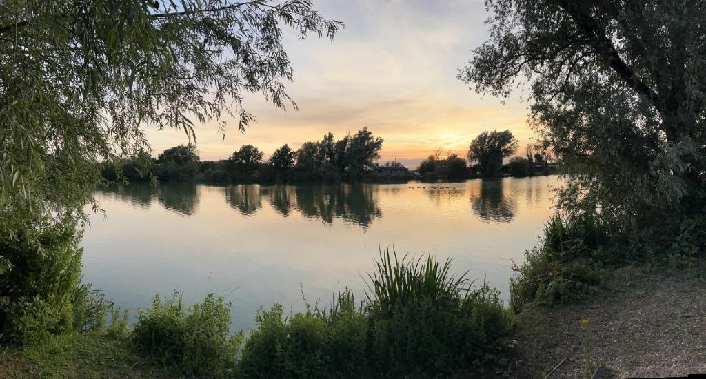 a view of a lake with a sunset in the background at Woodlakes Park By Liv Retreats in King's Lynn