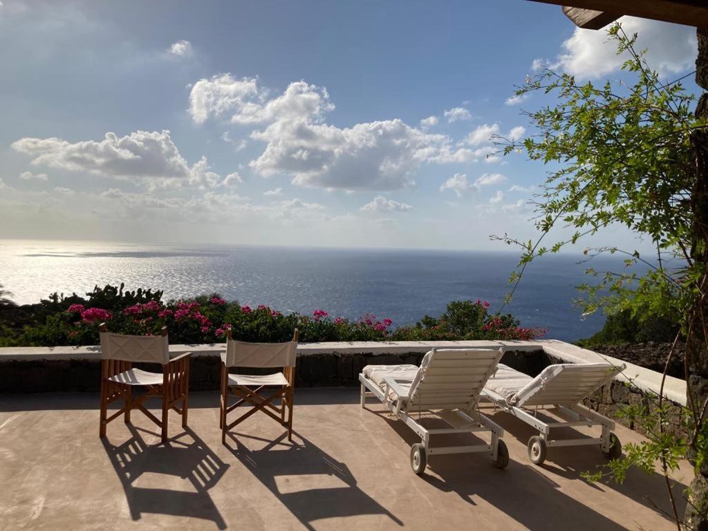 two chairs and a table on a patio overlooking the ocean at Dammuso Faraglione del Fico d'India in Pantelleria