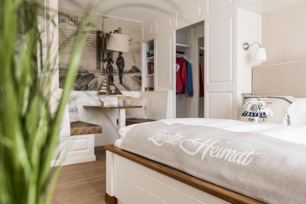 a bedroom with a bed and a table with a dresser at Hotel Zweite Heimat in Sankt Peter-Ording