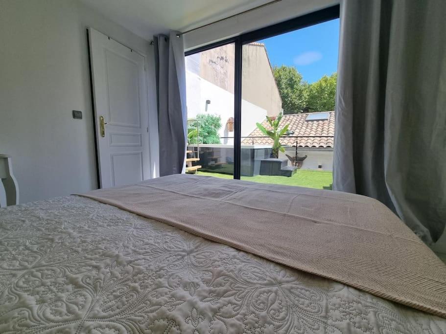 a bedroom with a bed and a large window at l'evasion ,maison de ville jacuzzi couchages x6 in Le Grau-du-Roi