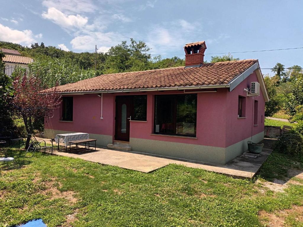 a small pink house with a bench in a yard at Obmorski oddih in Dekani