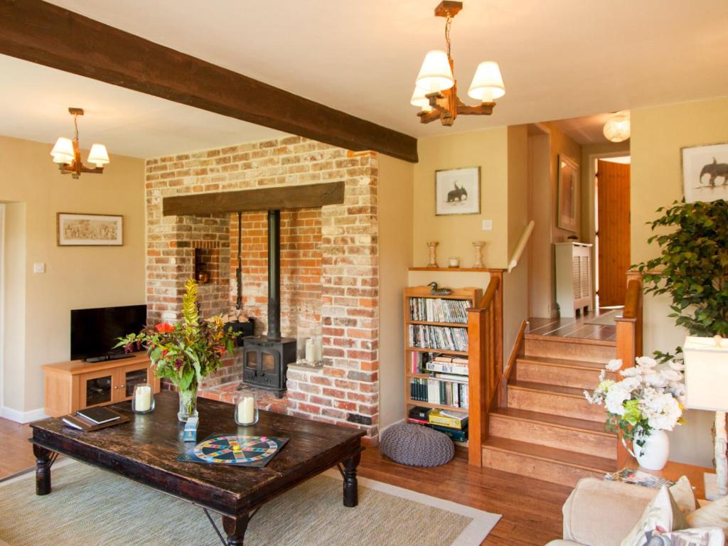 a living room with a brick fireplace and a table at The Hayloft- Dws in Marshwood