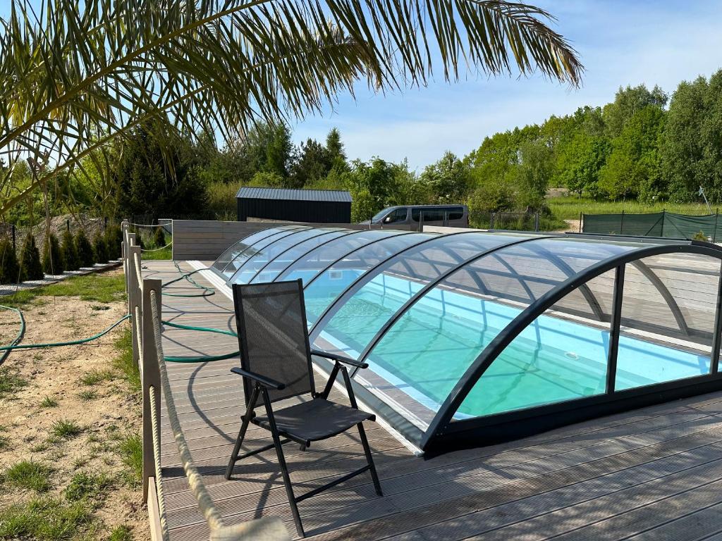 a glass house with a chair and a swimming pool at Grey Sea Rusinowo in Rusinowo