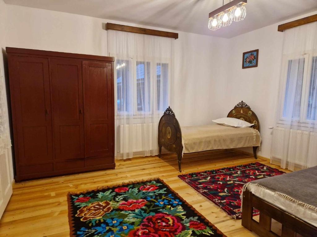 een kamer met een bed, een kast en een tapijt bij Casa Veche in Neagra Şarului