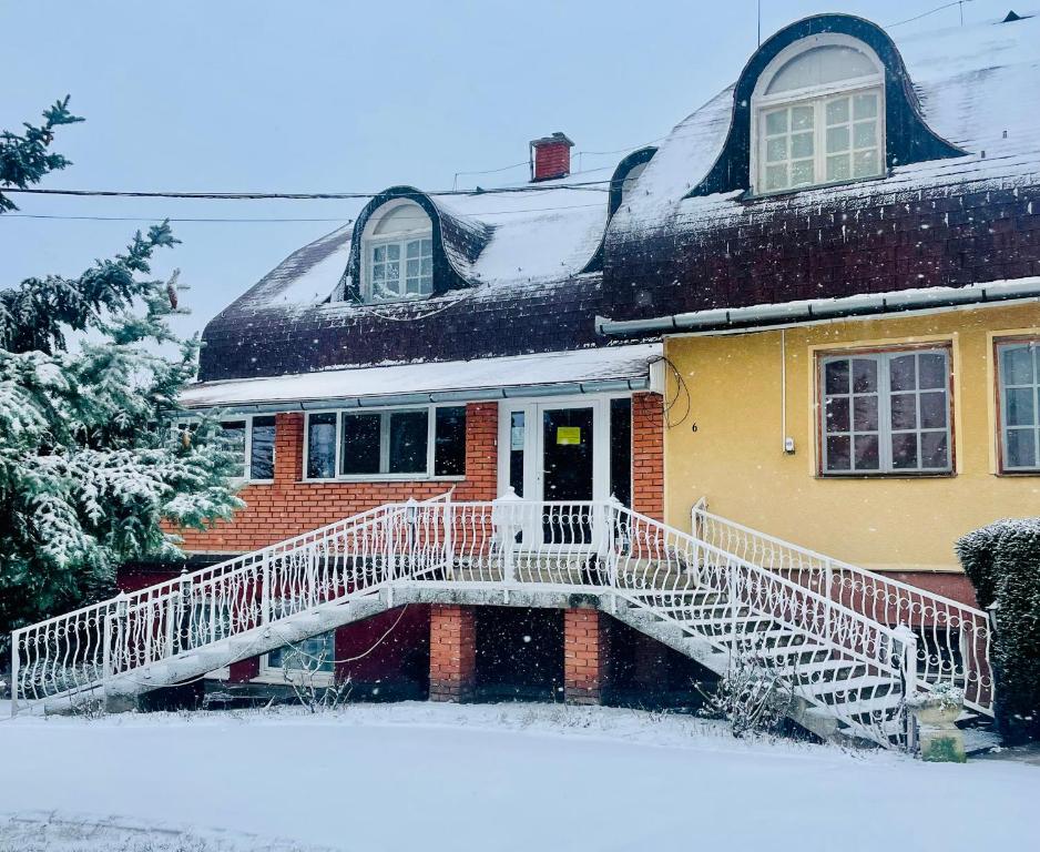 a house with a snow covered porch and stairs at Katalin Panzi&oacute; in Budapest