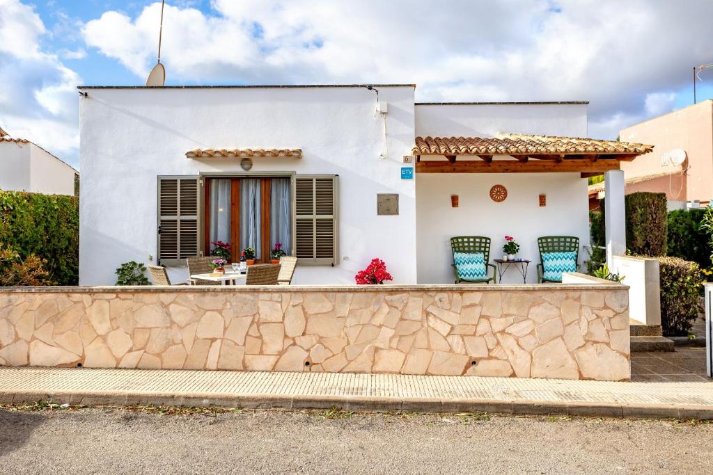 a white house with chairs and a stone wall at Casa La Palmera in Cala Figuera