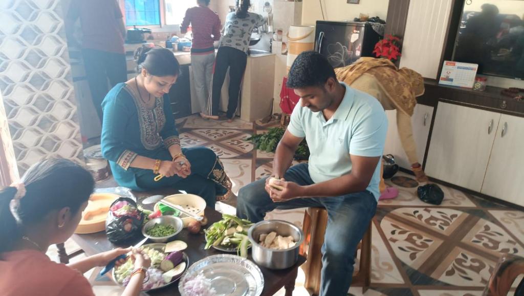 Un groupe de personnes assises autour d'une table préparant la nourriture dans l'établissement Janakpurdham Homestay, à Janakpur