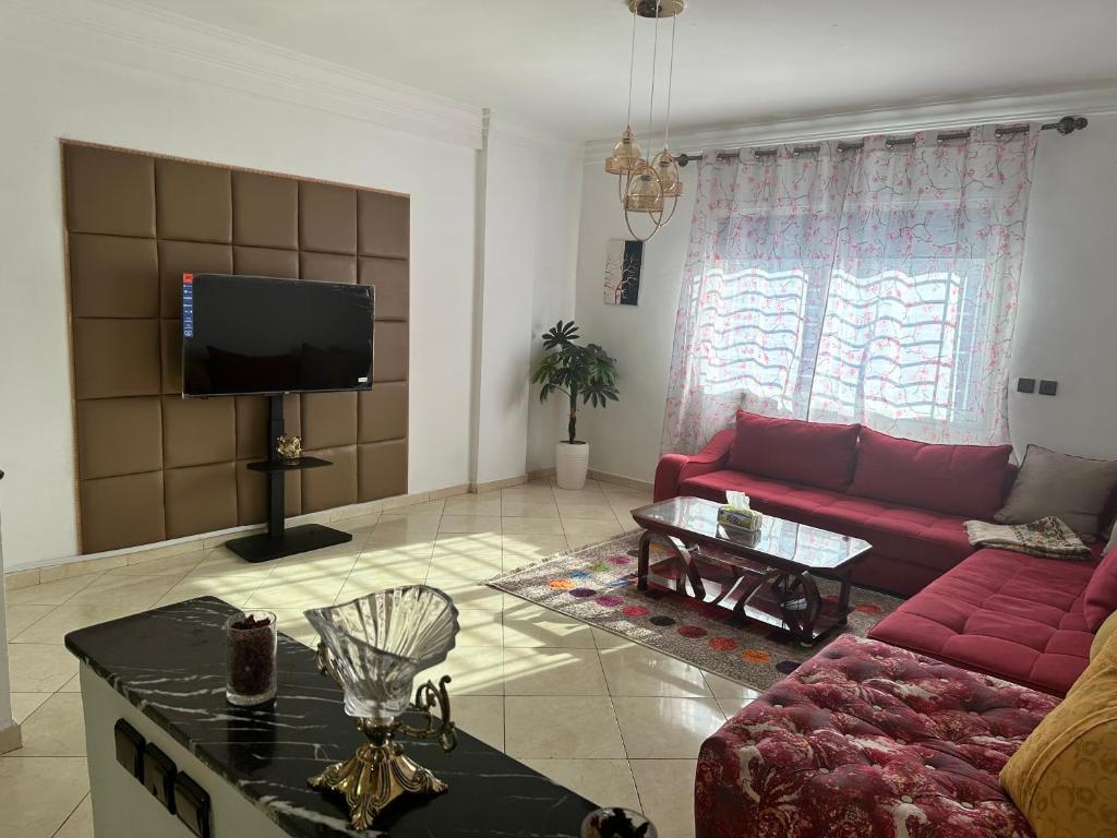 een woonkamer met een rode bank en een tv bij Appartement à beni mellal in Beni Mellal