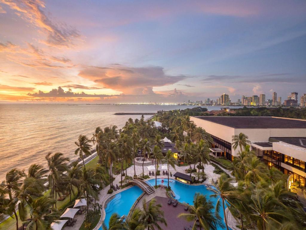 - une vue aérienne sur un complexe avec une piscine et l'océan dans l'établissement Sofitel Philippine Plaza Manila, à Manille