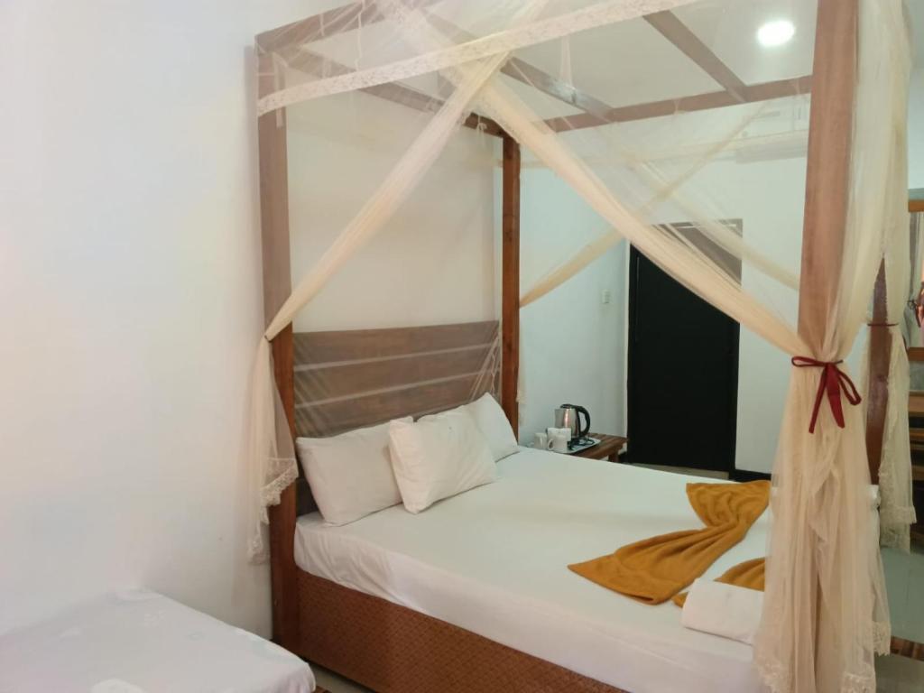 two beds in a room with a canopy bed at Yes Beach House in Mirissa